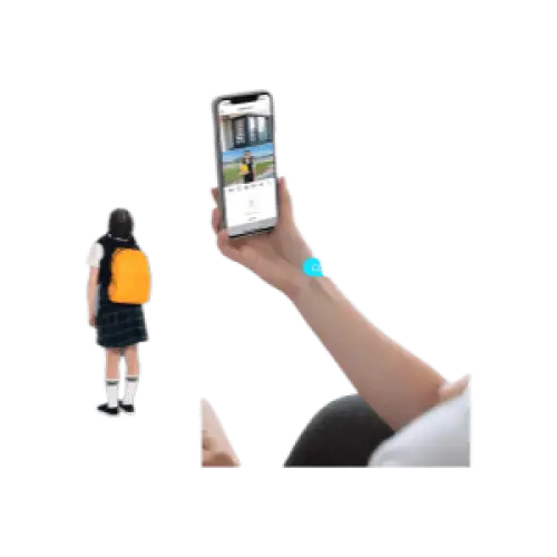 Un enfant portant un sac à dos jaune et une jupe sombre se tient à côté d’un adulte tenant un smartphone levé avec un bracelet de poignet bleu.