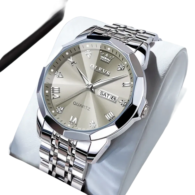 Montre à quartz pour homme, de couleur argentée, avec affichage de la date du jour, lunette à facettes multiples, index en chiffres romains et en diamants, et bracelet à maillons en métal.