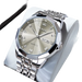 Montre à quartz pour homme, de couleur argentée, avec affichage de la date du jour, lunette à facettes multiples, index en chiffres romains et en diamants, et bracelet à maillons en métal.
